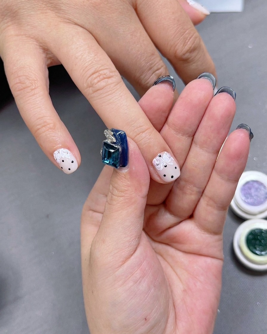 Eine Nailart-Künstlerin trägt kleine grüne Gelakzente um die Rosenblätter auf.
