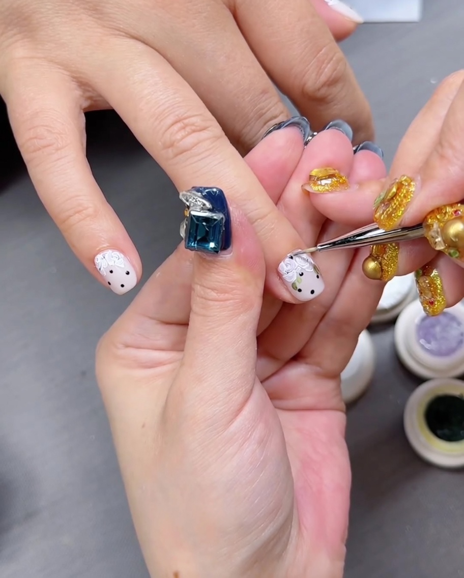Eine Hand mit floral bemalten Nägeln ruht in einer professionellen LED-Nagelhärtungslampe.