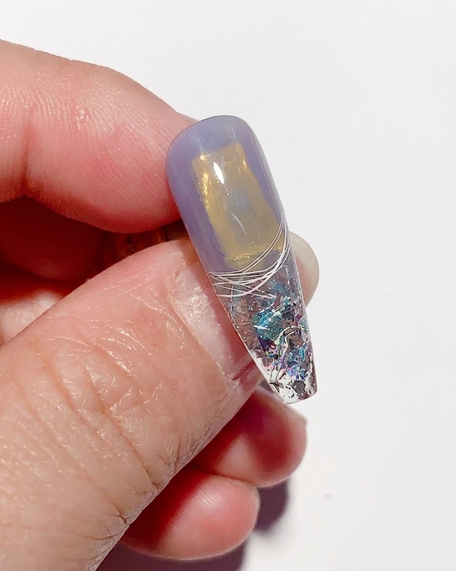 Eine texturierte, ausgehärtete Nagelspitze, nachdem die Frischhaltefolie abgezogen wurde, was ein einzigartiges, zerknittertes Glas-Finish enthüllt.