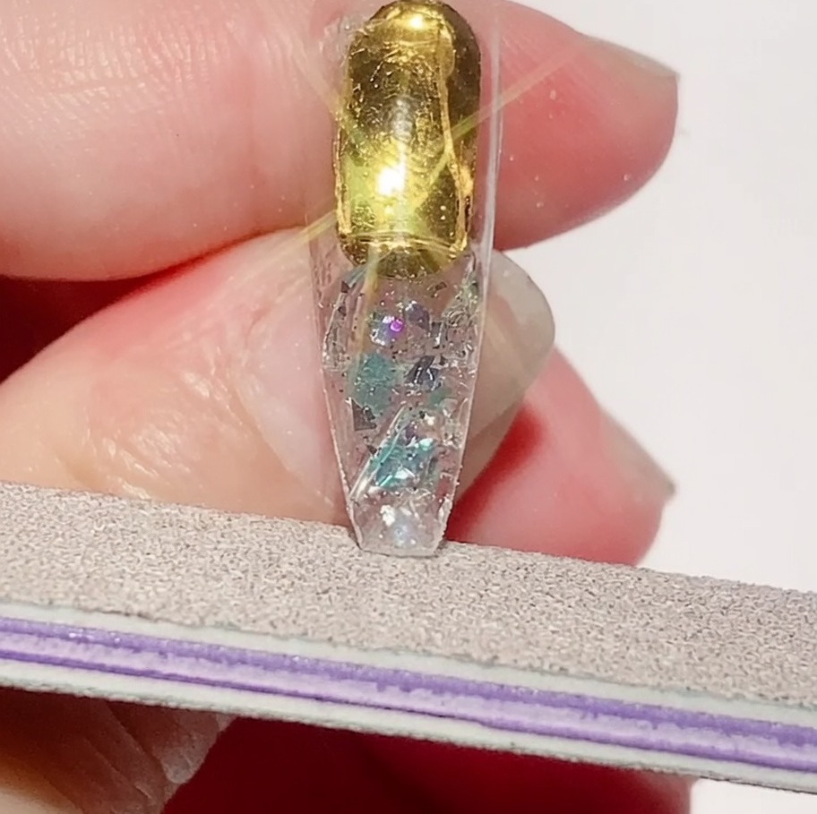 Eine Nagelfeile verfeinert die Kanten einer texturierten Nagelspitze, um einen glatten Umfang zu gewährleisten.