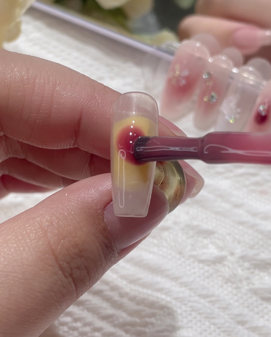 Rosa Gel wird in die feuchte Oberfläche des Nagels getupft.