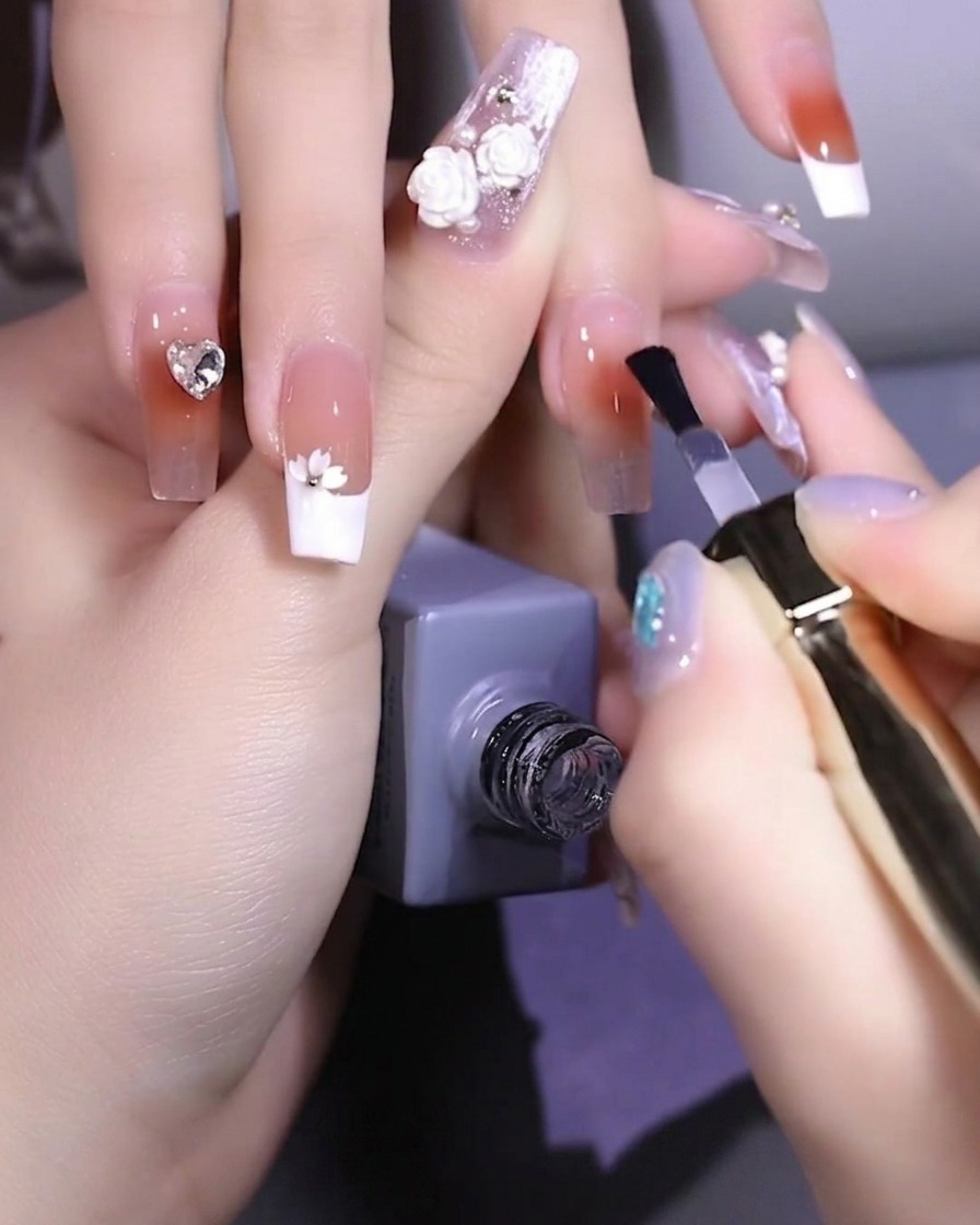 Ein Nagelpinsel trägt klares, stärkendes Basisgel auf einen Fingernagel auf.