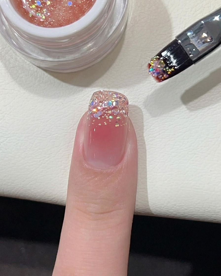 Ein kleiner Punkt leuchtend rosa Gellack in der Mitte des nudefarbenen Nagels.