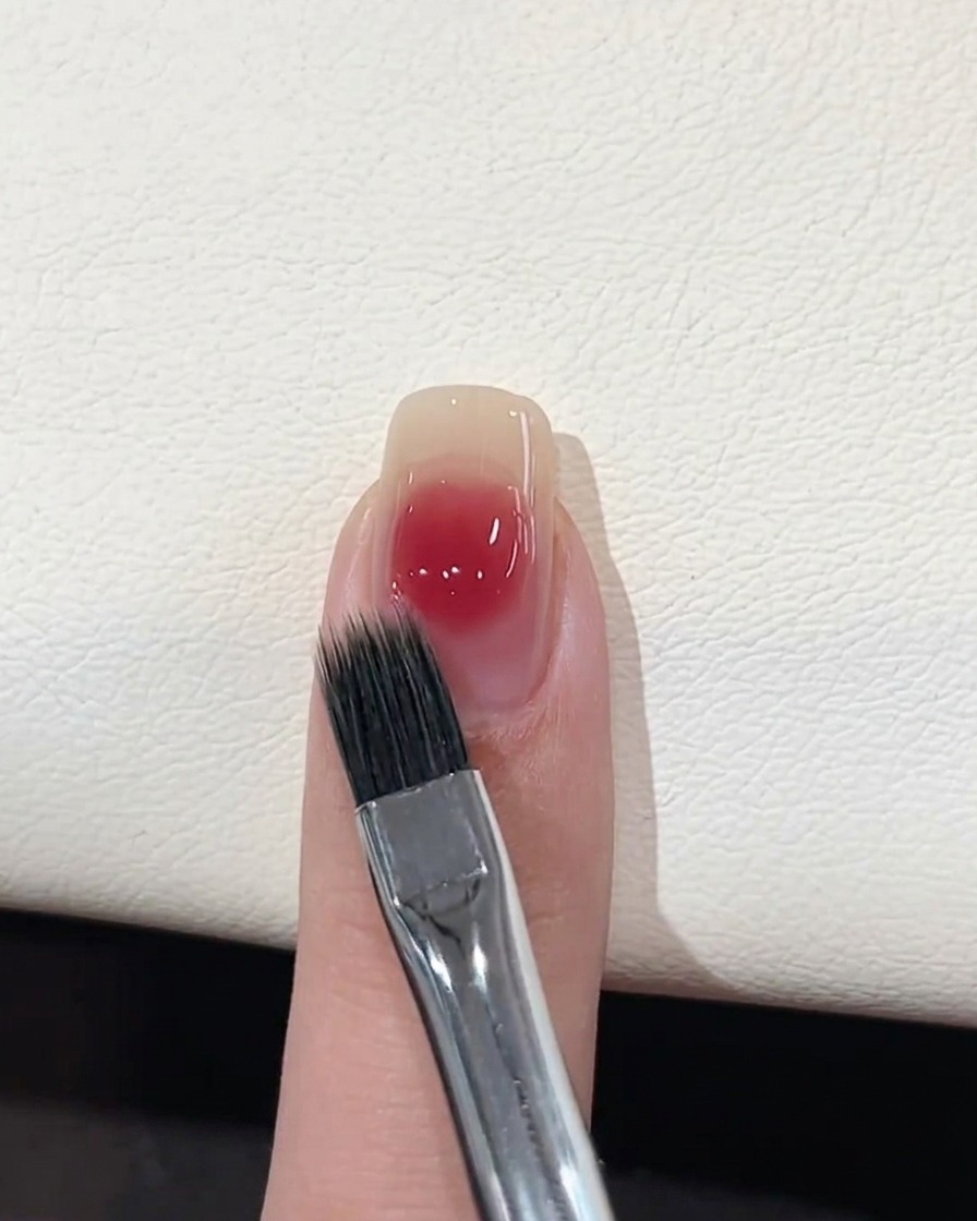 Ein flacher Pinsel zum Verblenden lässt den Rand des rosa Geltropfens weicher erscheinen.