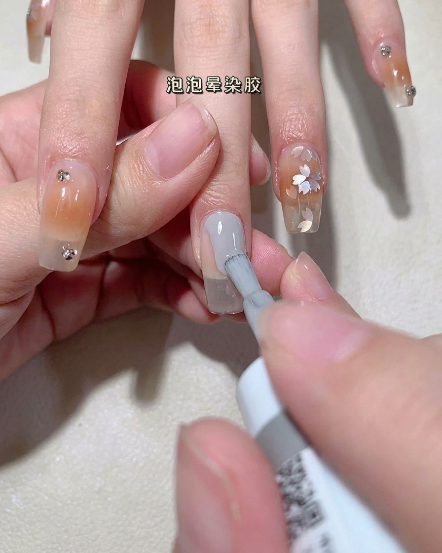 Nahaufnahme einer Bürste, die klares Bubble Gel auf einen natürlichen Nagel aufträgt.