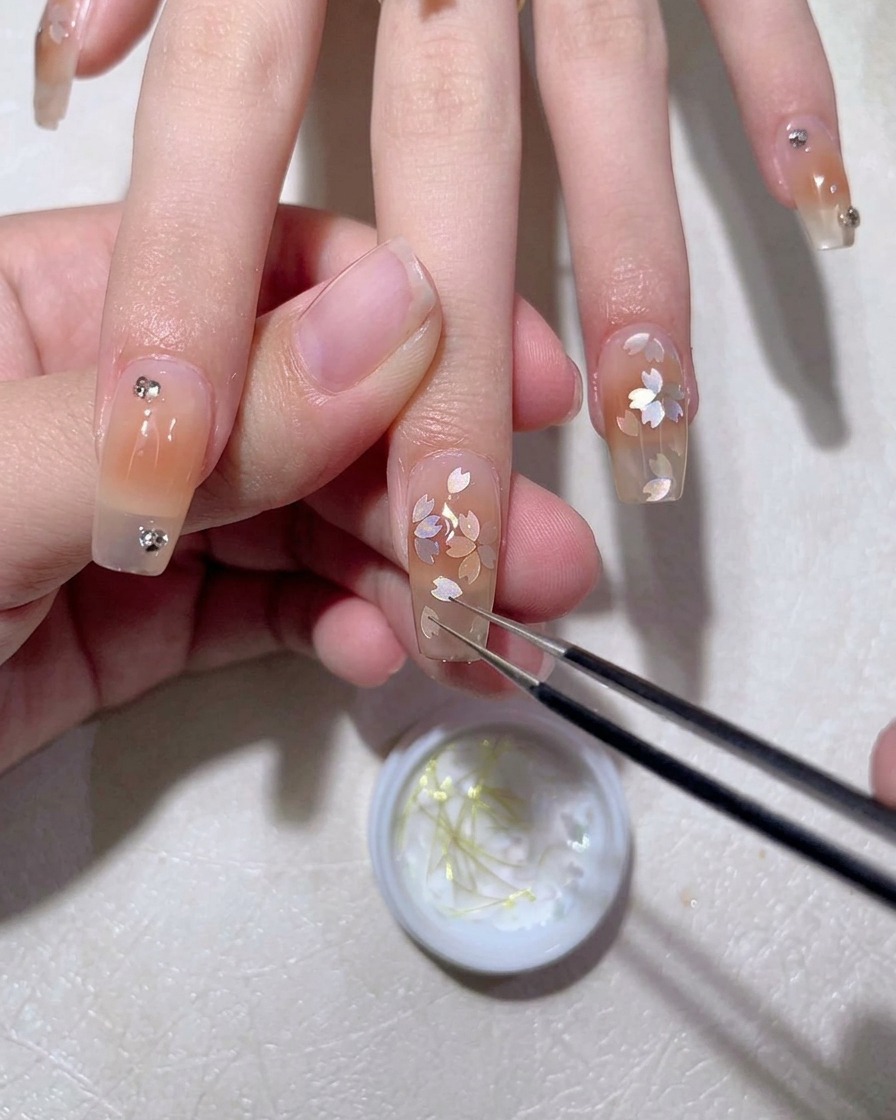 Ein Gelpinsel trägt eine glänzende Schicht Top Coat über das fertige Nageldesign auf.