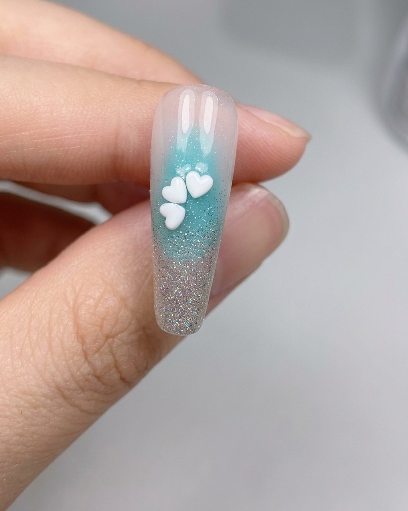 Nahaufnahme eines Nagels mit fünf weißen Kirschblüten-Pailletten, die zu einer vollständigen Blume angeordnet sind.