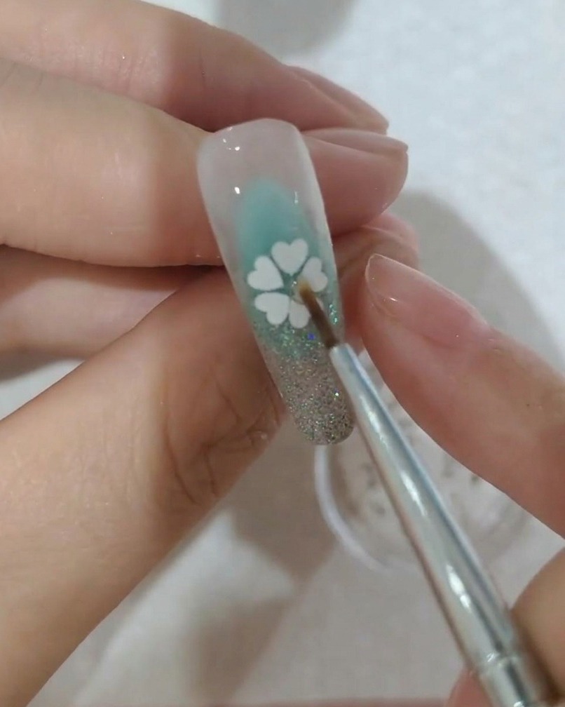 Nahaufnahme eines kleinen Kristalls, der in der Mitte der Paillettenblüte auf einem Nagel platziert wird.