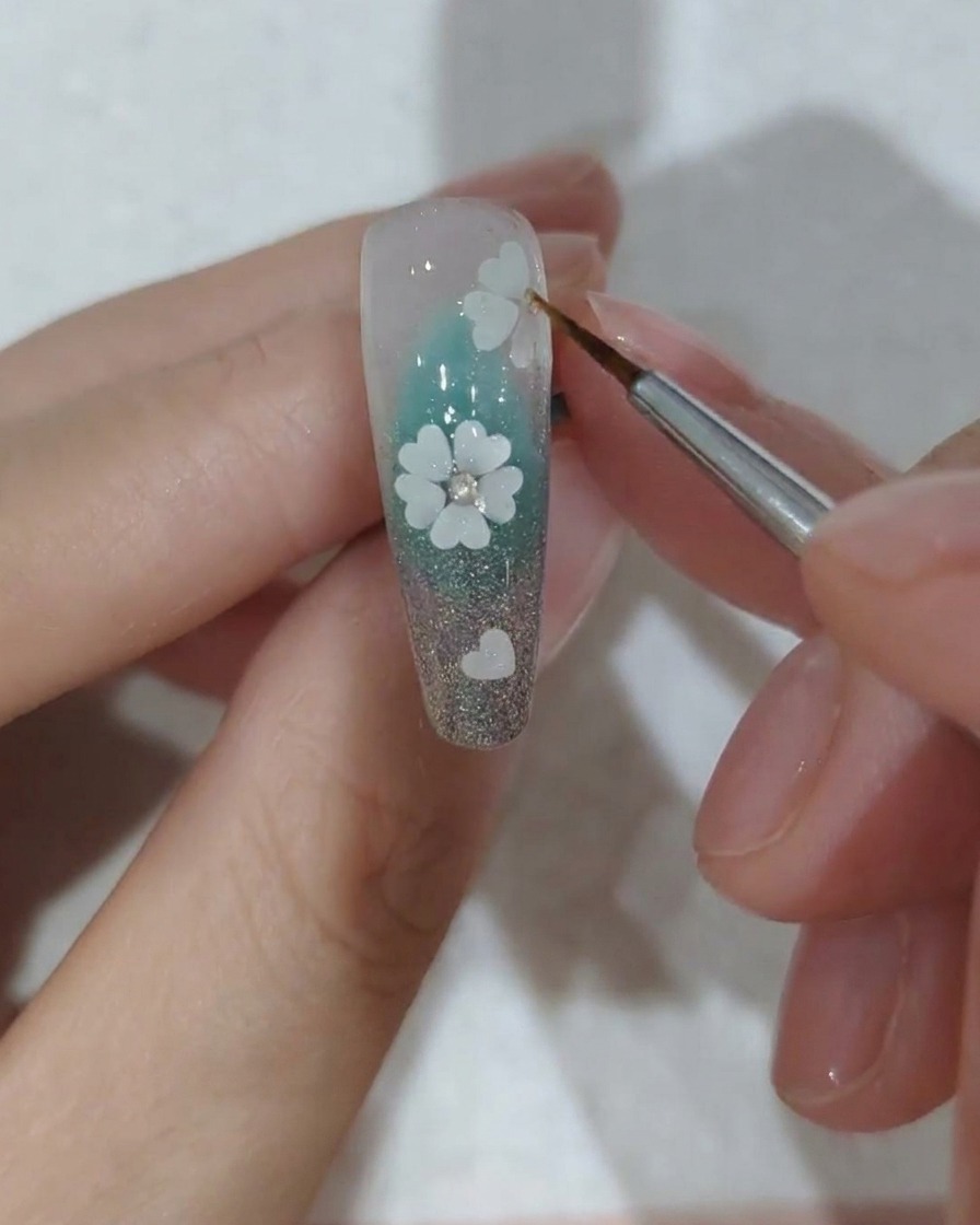 Nahaufnahme eines dekorierten Nagels mit Kristallen beim Platzieren unter einer professionellen UV-Nagellampe zur Aushärtung.