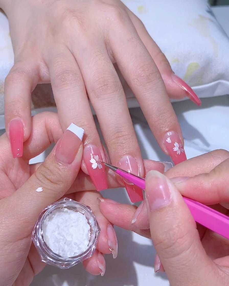 Auftragen eines klaren, klebrigen Haftgels über eine pinke Ombré-Maniküre mit einem feinen Pinsel.
