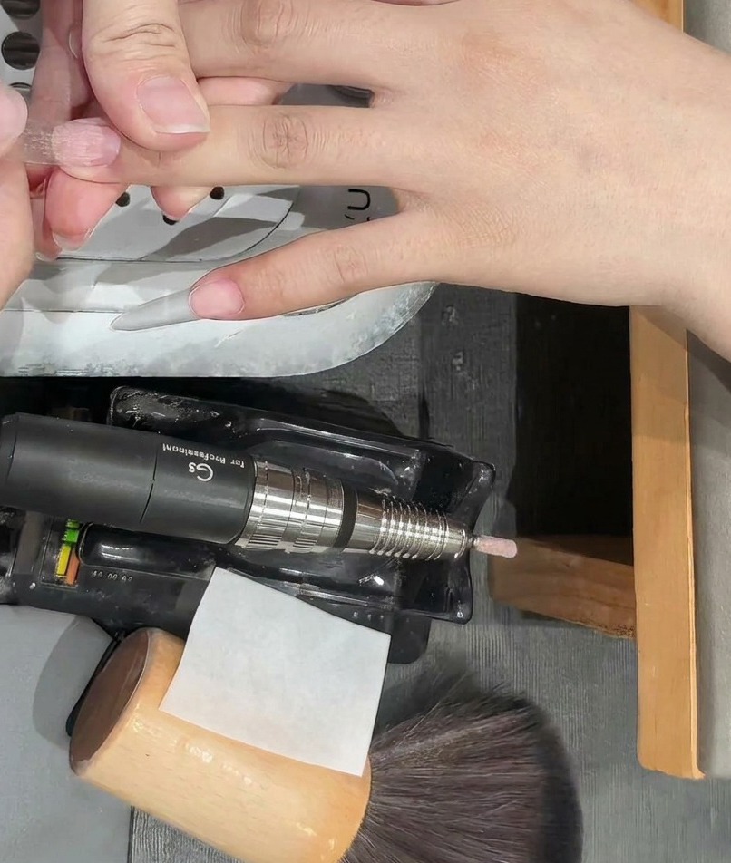 Nahaufnahme eines klaren Kunststoff-Nagel-Tips, der auf einen Naturnagel aufgebracht wird.