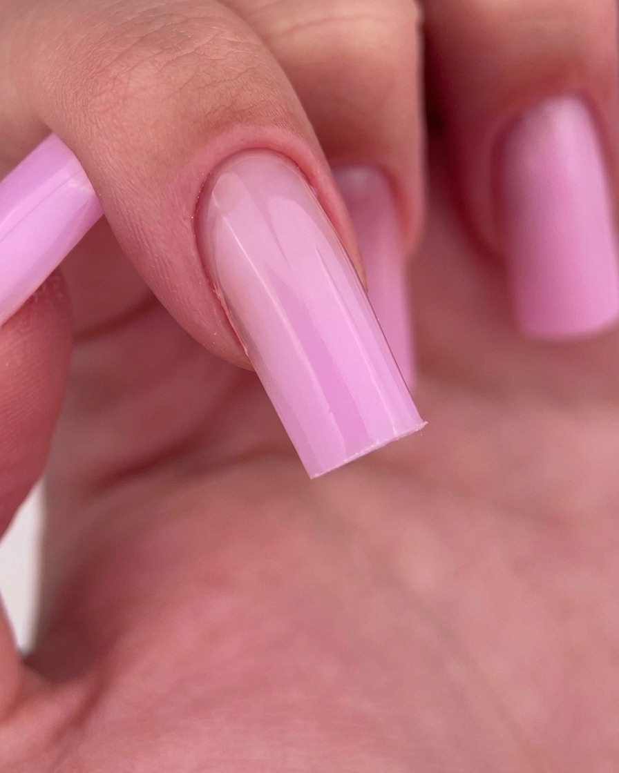 Nahaufnahme eines Fingers, der mit einem fusselfreien Pad gereinigt wird, wobei das glänzende rosa Gelfinish zum Vorschein kommt.