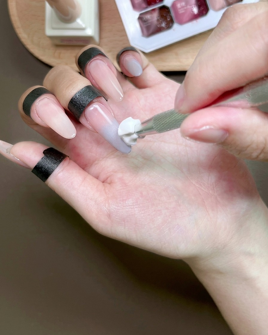 Ein Schwämmchen verblendet blaues Gel auf einem Fingernagel, um einen Ombré-Effekt zu erzielen.