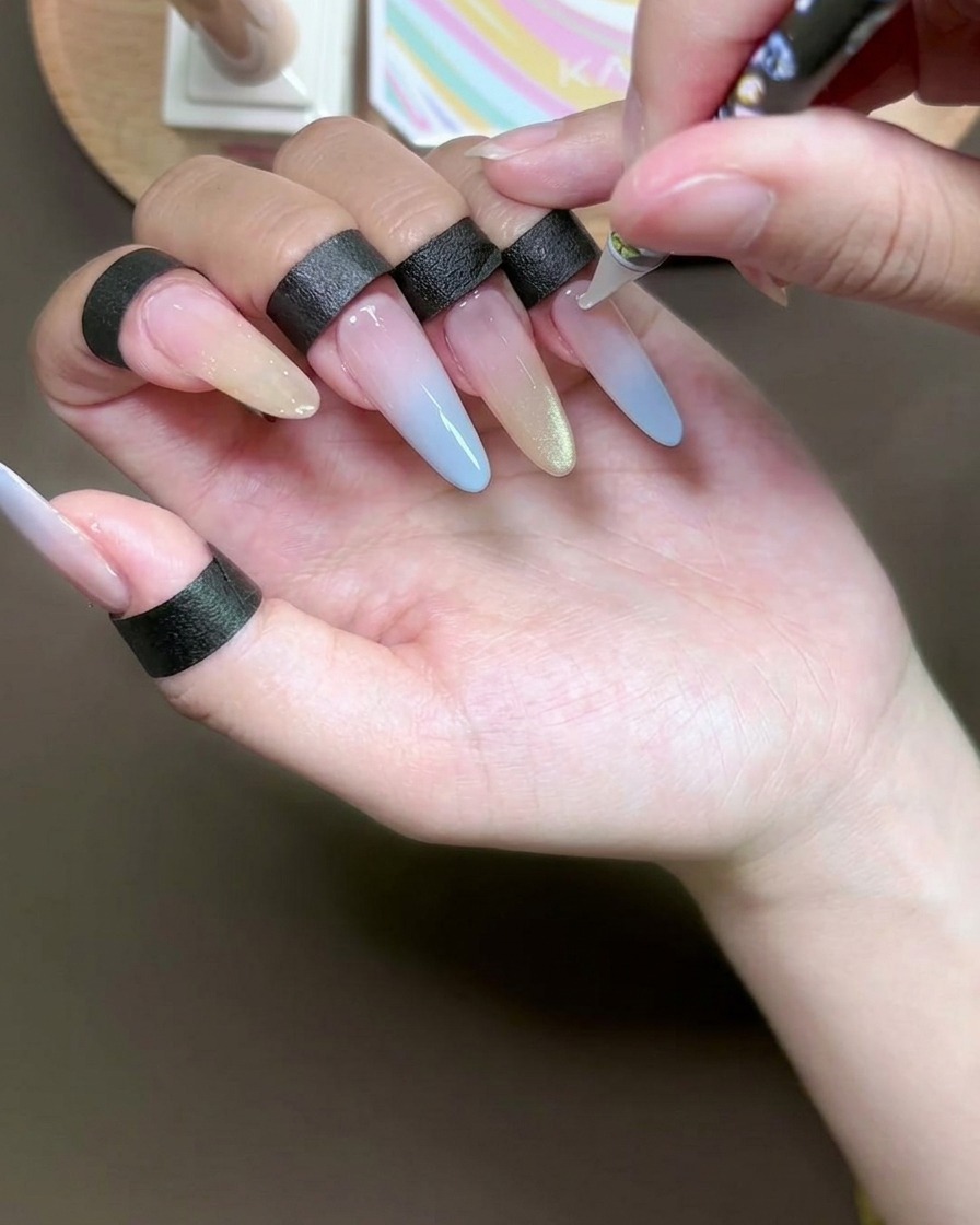 Nahaufnahme eines Dotting-Tools, das winzige Punkte klaren Klebers auf einen Gelnagel aufträgt.