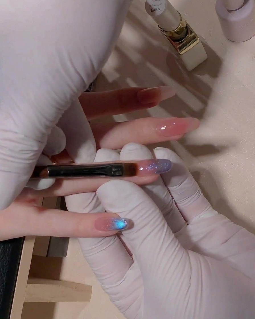 Nahaufnahme eines flachen Gelpinsels, der den Übergang des blauen Cat-Eye Gels auf der Nageloberfläche sanft verblendet.