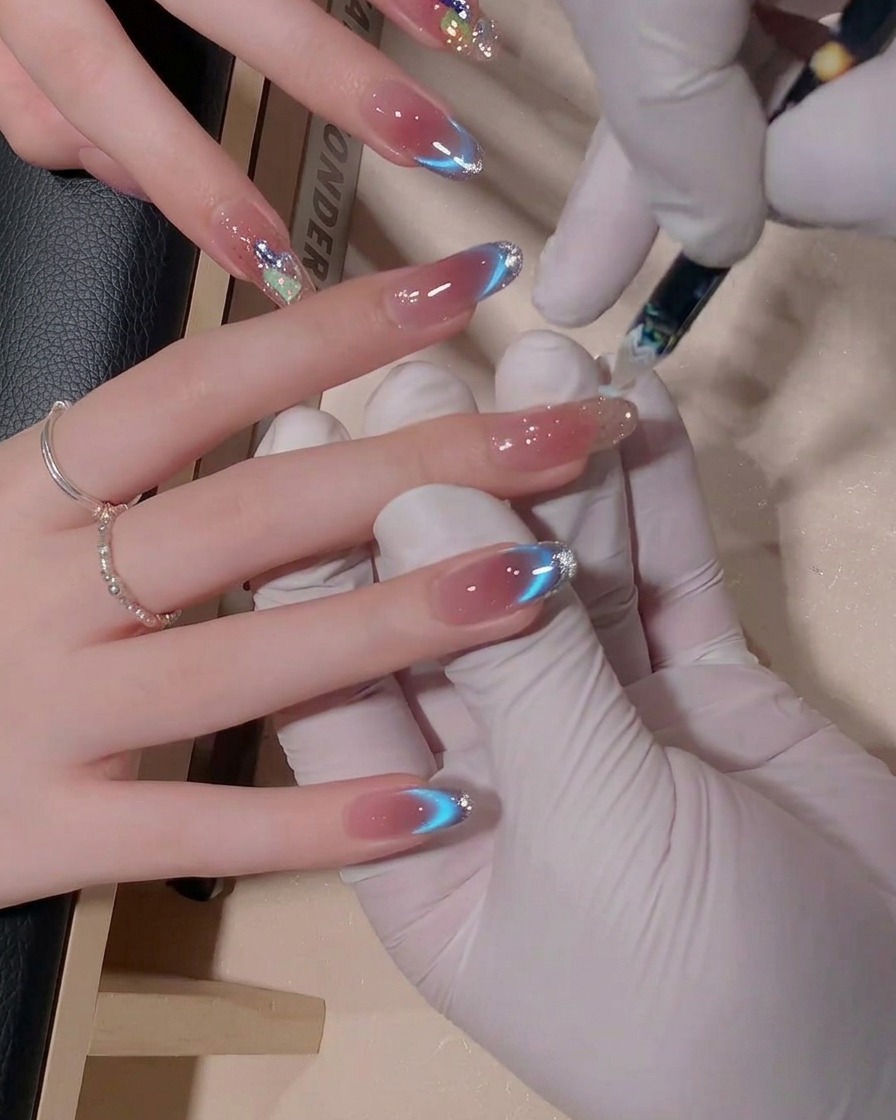 Nahaufnahme eines Nagelpinsels, der bläuliches Gel auf einem Fingernagel verblendet, um einen weichen, nahtlosen Ombré-Effekt zu erzielen.
