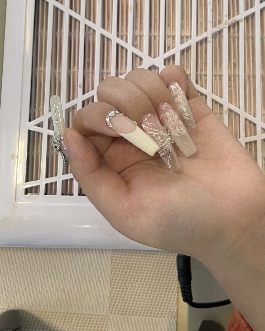 Ein Nagelknipser kürzt eine lange, verzierte Nagelverlängerung.