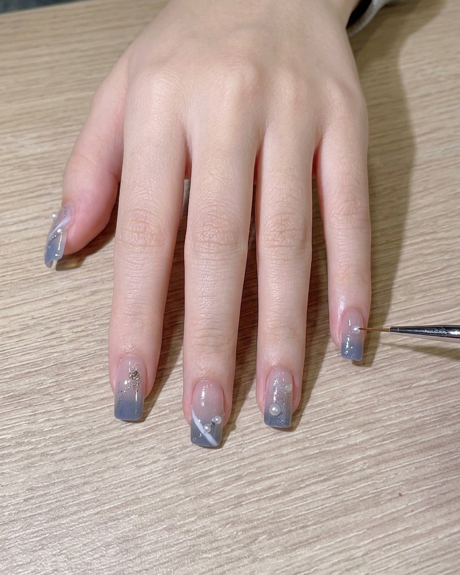 Ein Pinsel trägt zum Abschluss einen glänzenden Top Coat auf das fertige Nageldesign auf.
