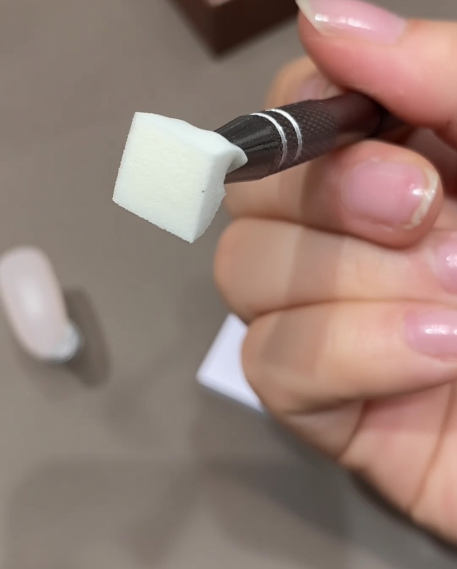 Nahaufnahme einer Hand, die einen Make-up-Schwamm mit Klebeband von Staub reinigt.