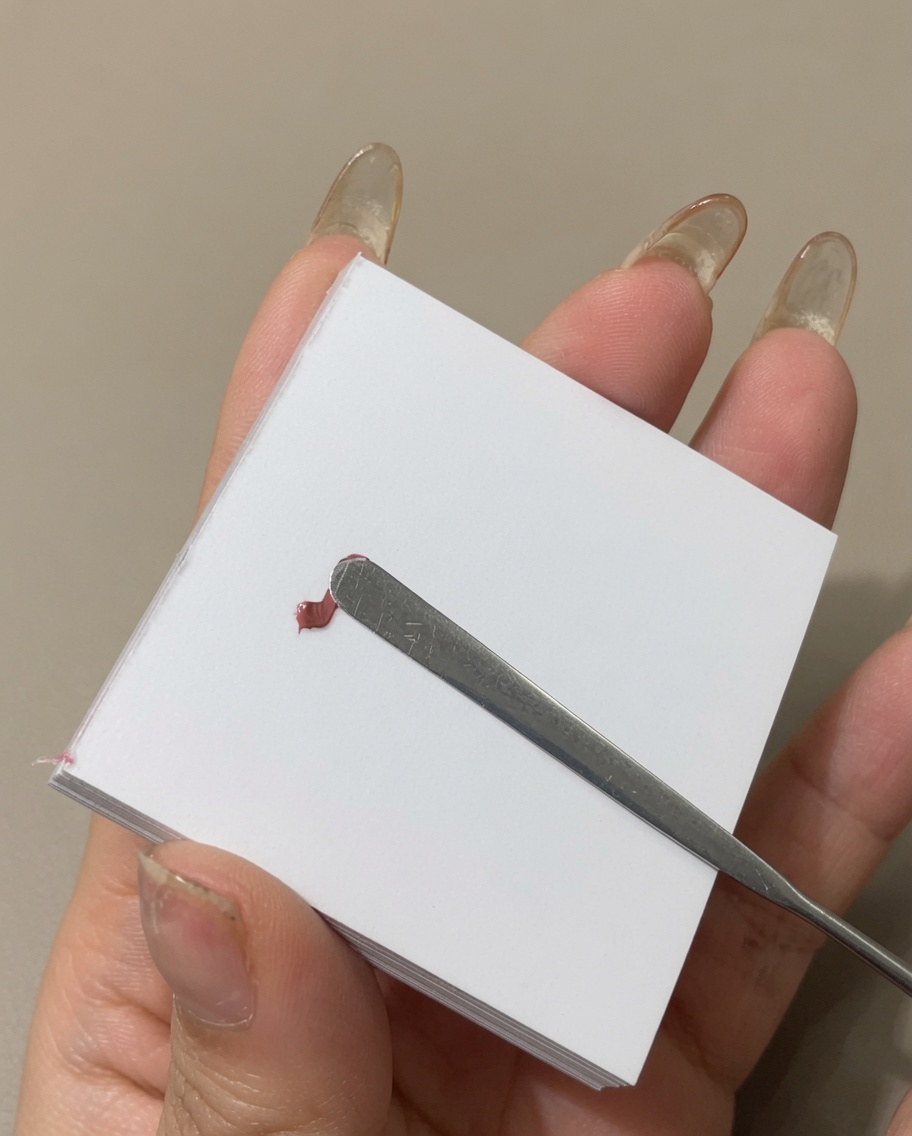 Ein Metallspatel verstreicht eine Linie Farbgel auf einer Palettenoberfläche.