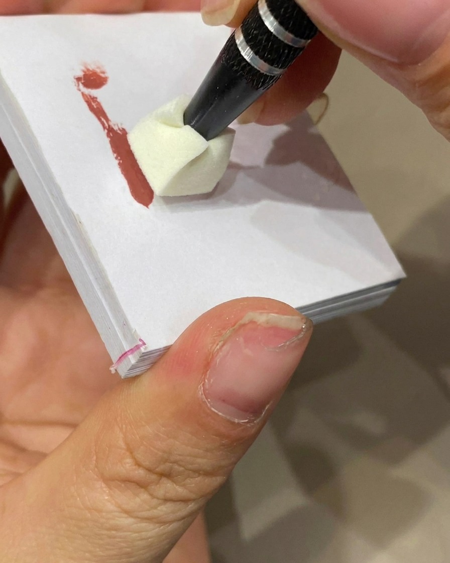 Ein Schwamm stempelt Farbgel auf die Nagelspitze, um einen Ombré-Effekt zu erzeugen.