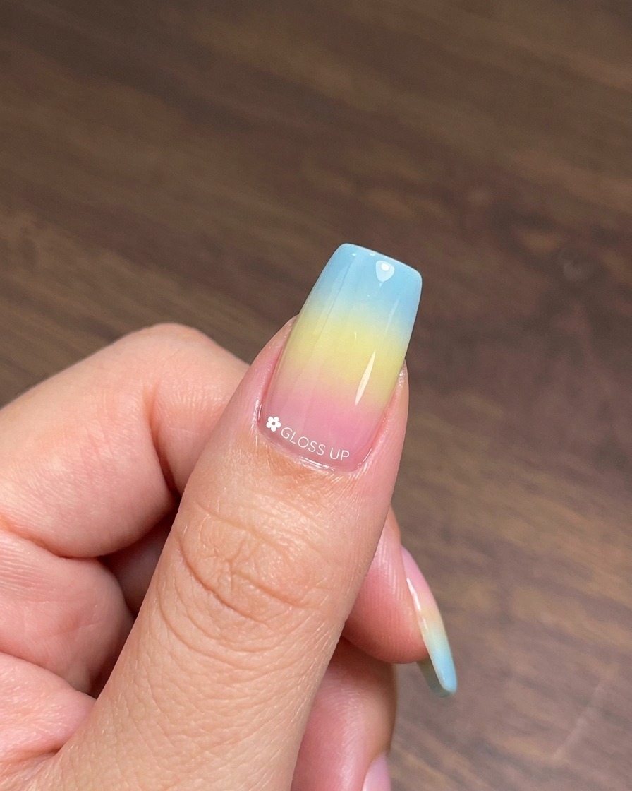 Ein Pinsel trägt eine Schicht Cat-Eye-Gel-Lack Nummer 25 über die ausgehärtete, bunte Gradient-Basis auf.
