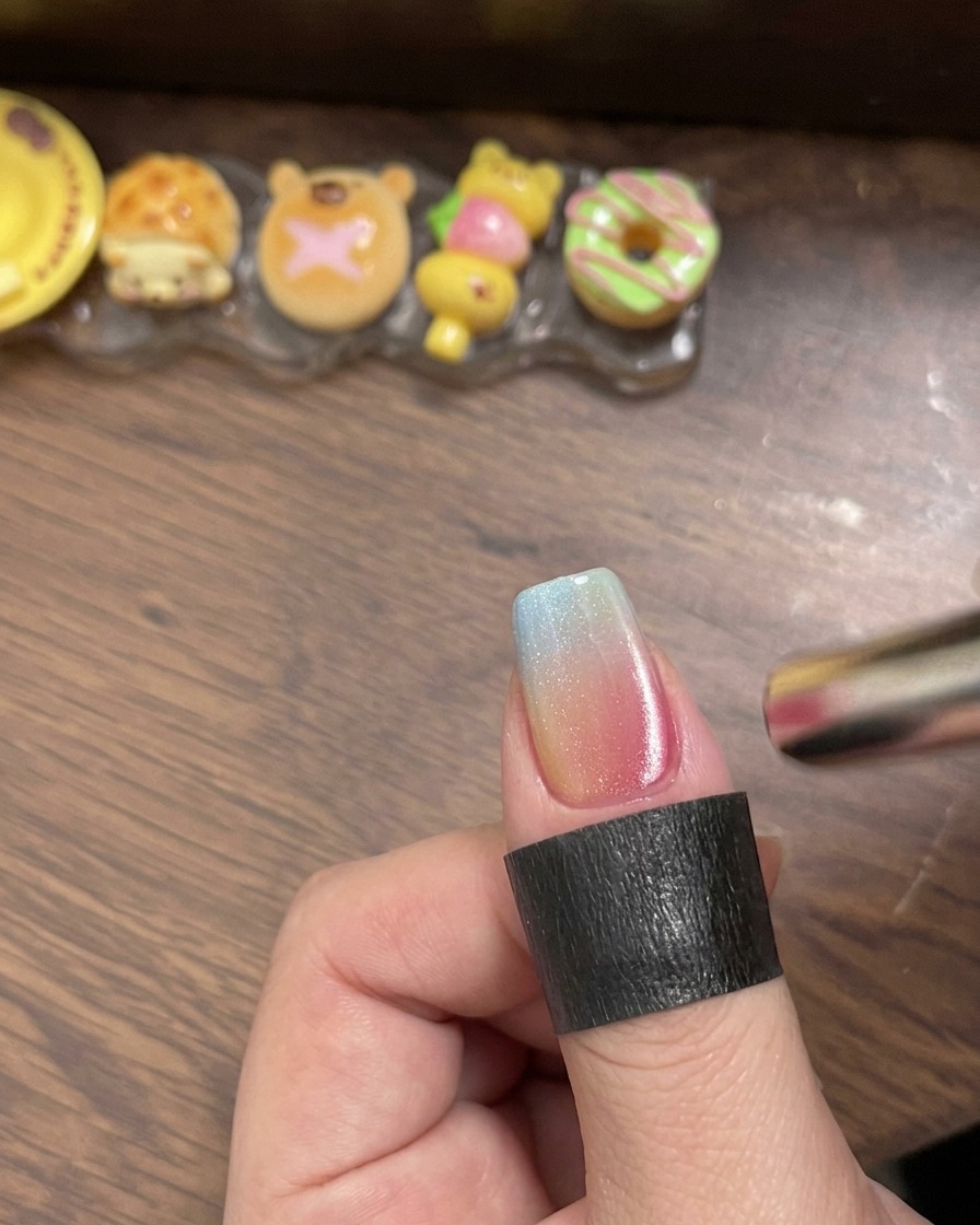 Ein Pinsel trägt einen klaren Hochglanz-Top-Coat über den mehrfarbigen Gradient-Nagel auf.