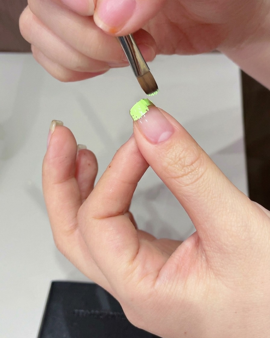 Ein Make-up-Schwamm wird verwendet, um das grüne Gel an der Nagelspitze zu betupfen und weicher zu machen.