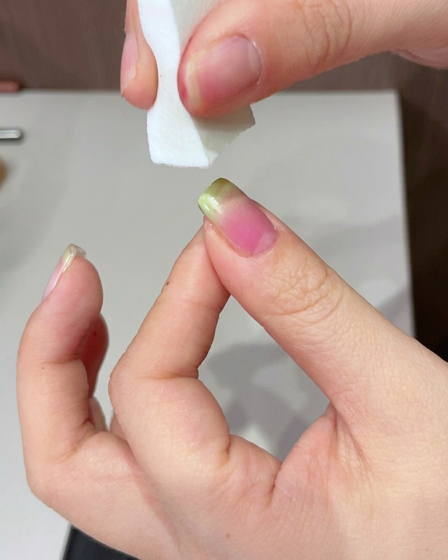 Eine Hand wird unter der UV-Lampe positioniert, um die grün intensivierte Spitze auszuhärten.