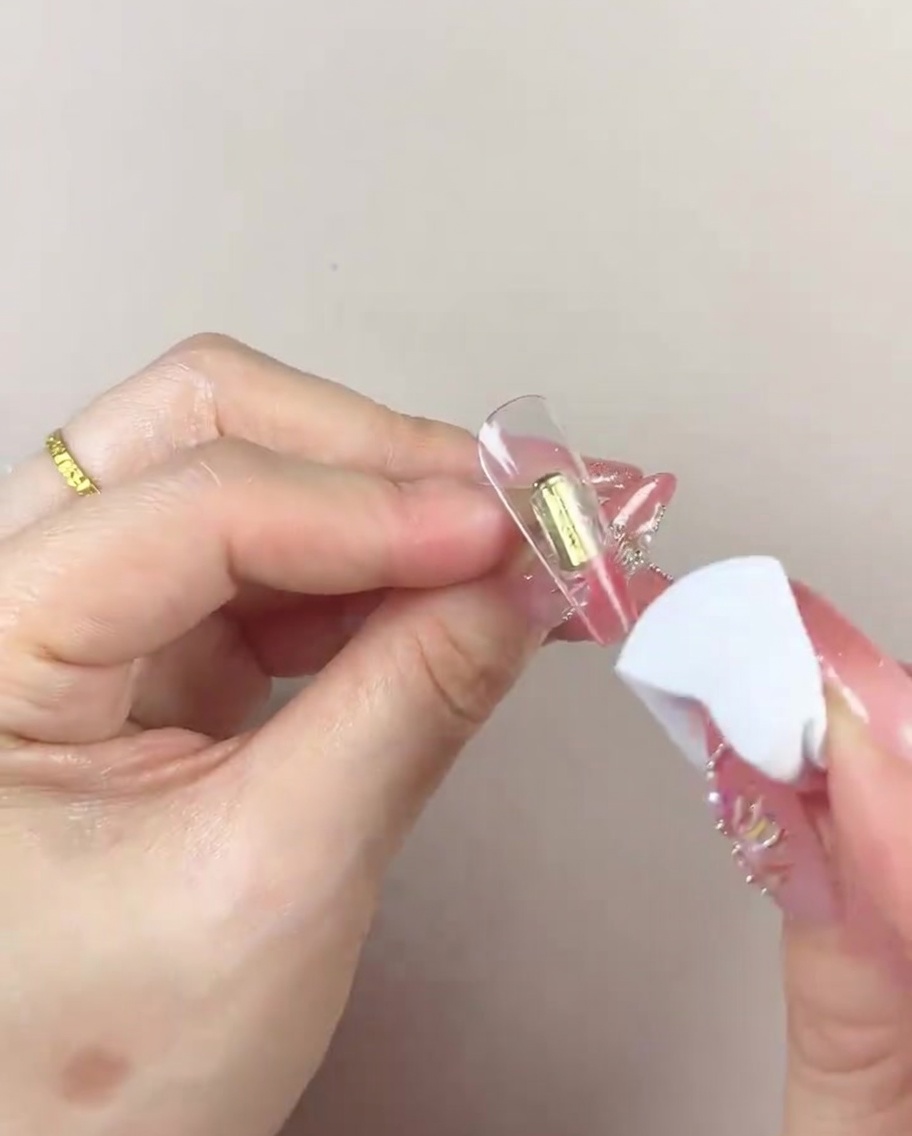 Ein Make-up-Schwamm bewegt sich links und rechts über den Nagel, um die Farbe zu verblenden.