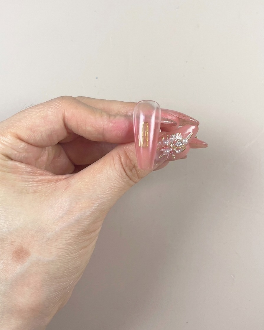 Ein Pinsel trägt eine frische Schicht pigmentiertes Patting-Gel auf den unteren Teil des Nagels auf.
