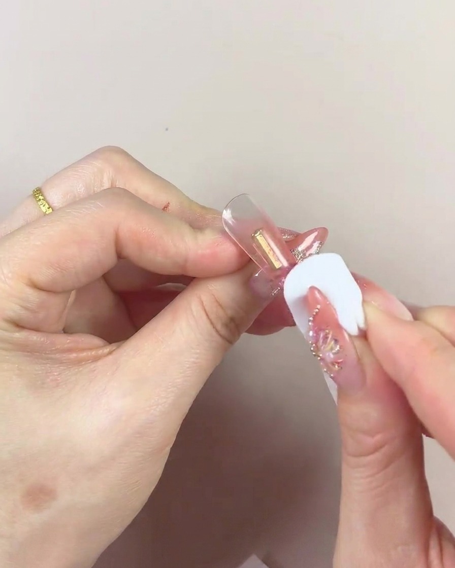 Nahaufnahme eines Kosmetikschwamms, der Gel auf eine Nagelspitze tupft.