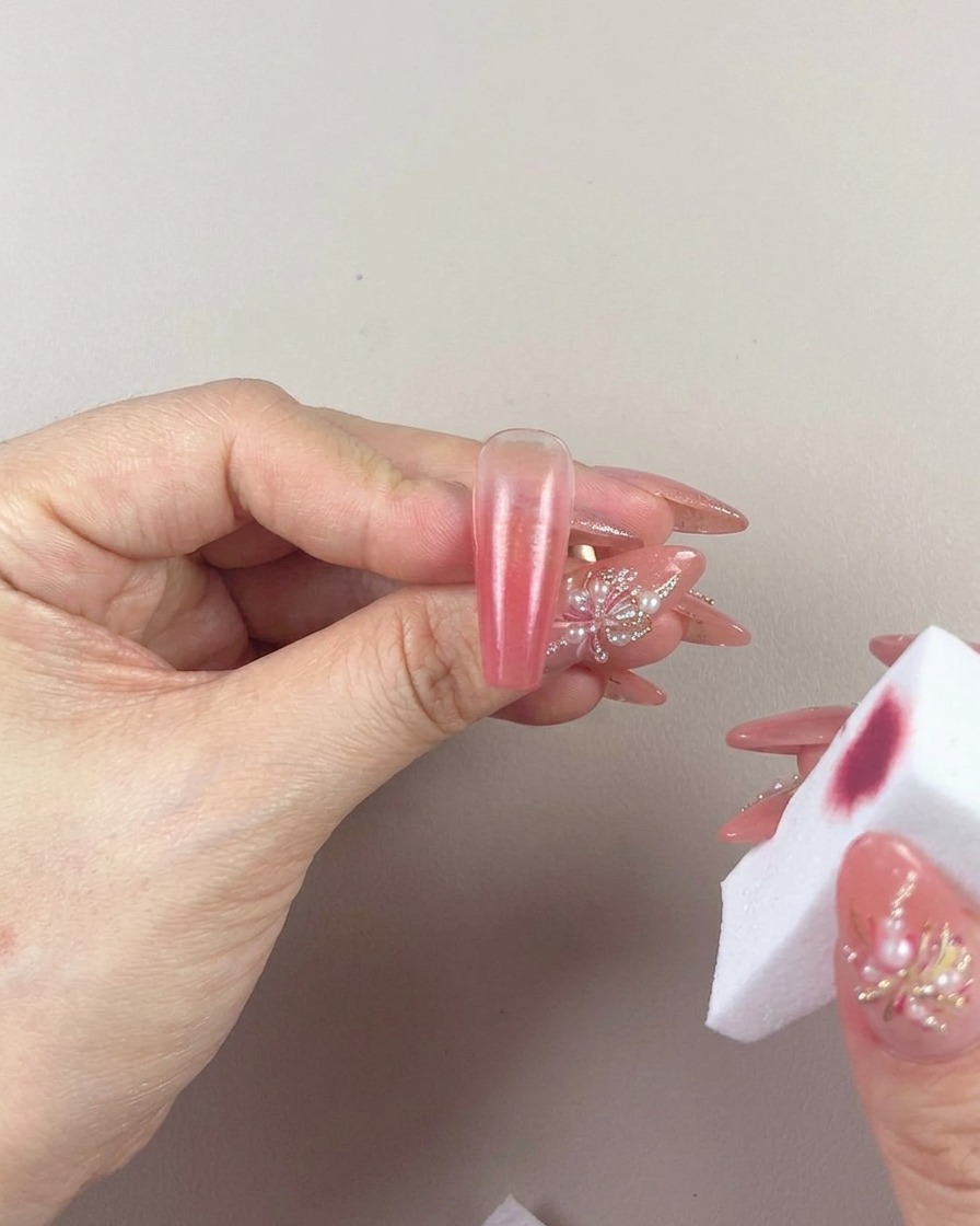 Nahaufnahme eines Make-up-Schwamms, der sanft den Farbverlauf auf einem Nagel verblendet.