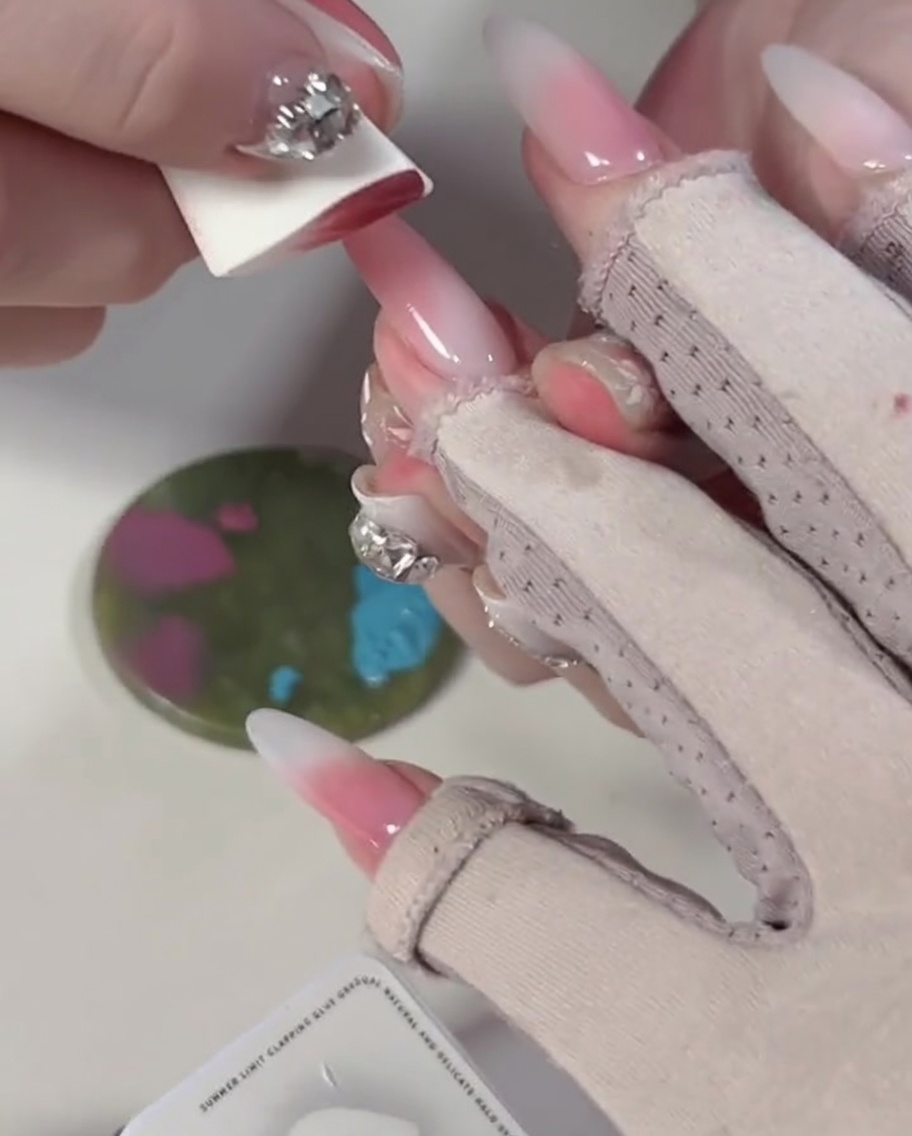 Eine Nahaufnahme, wie ein Schwamm auf die Farbblöcke von blauem und pinkem Gel auf einer Palette gedrückt wird.