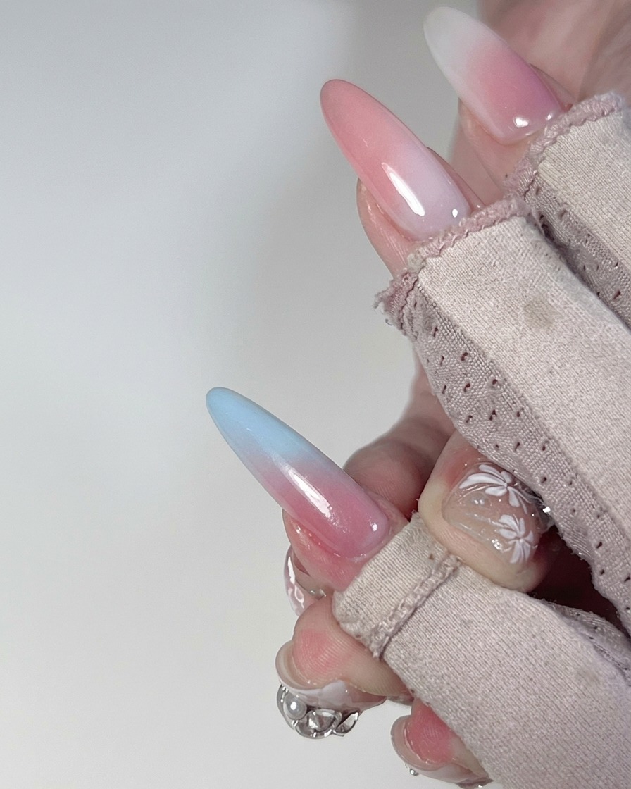 Nahaufnahme vom Verblenden des Übergangsbereichs von Blau zu Pink auf einem Fingernagel mit einem Schwamm.