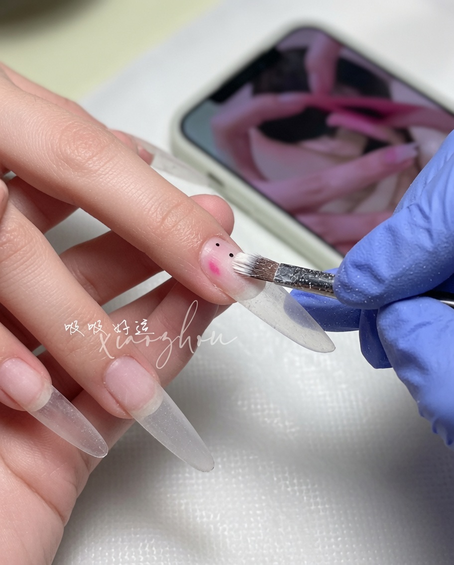 Ein Nagelpinsel verteilt einen weichen, nudefarbenen Gellack auf der Nagelplatte.