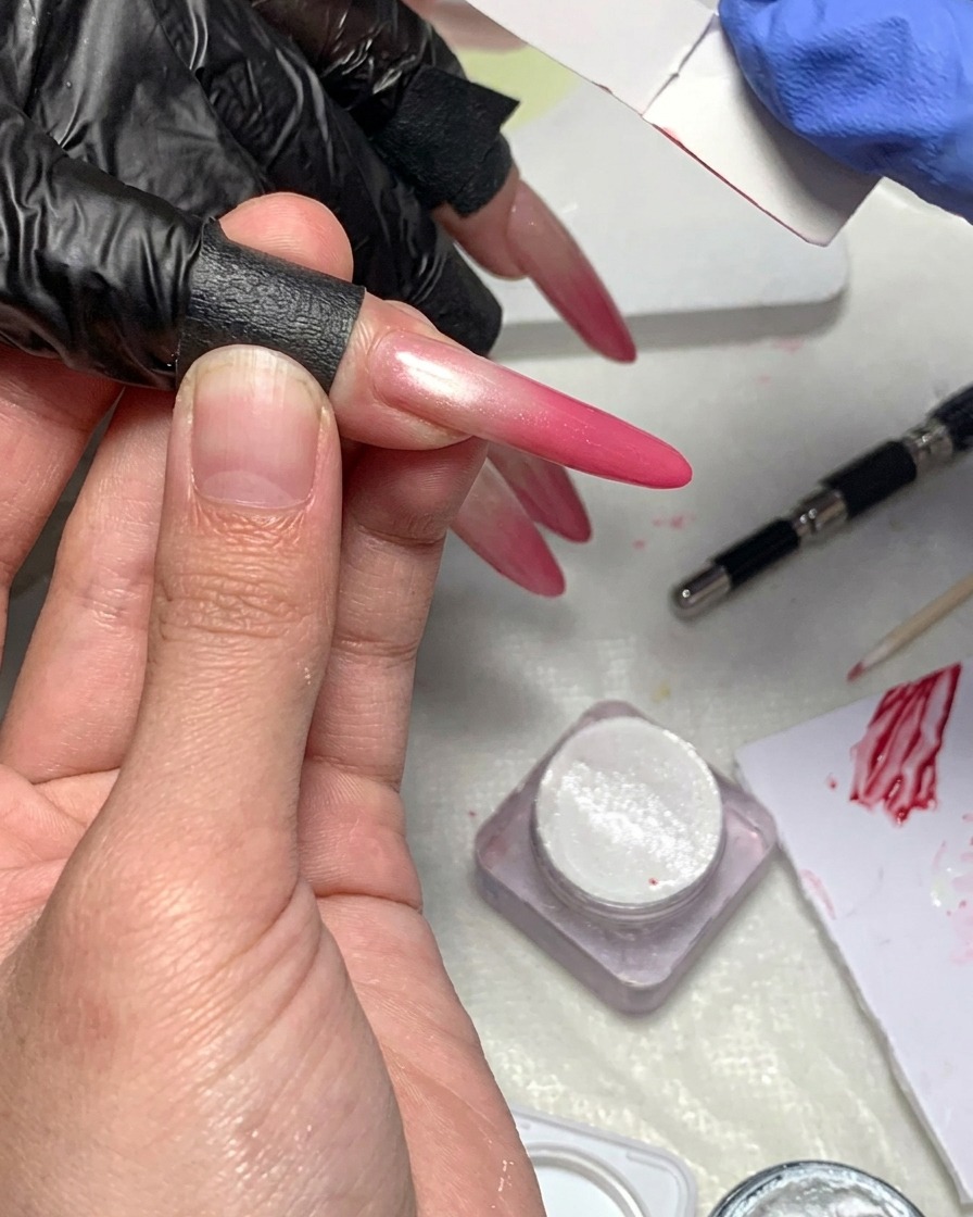 Nahaufnahme eines fusselfreien Tuchs, das zum Reinigen der Haut und der Kanten um einen Nagel mit Magenta-Gradient verwendet wird.