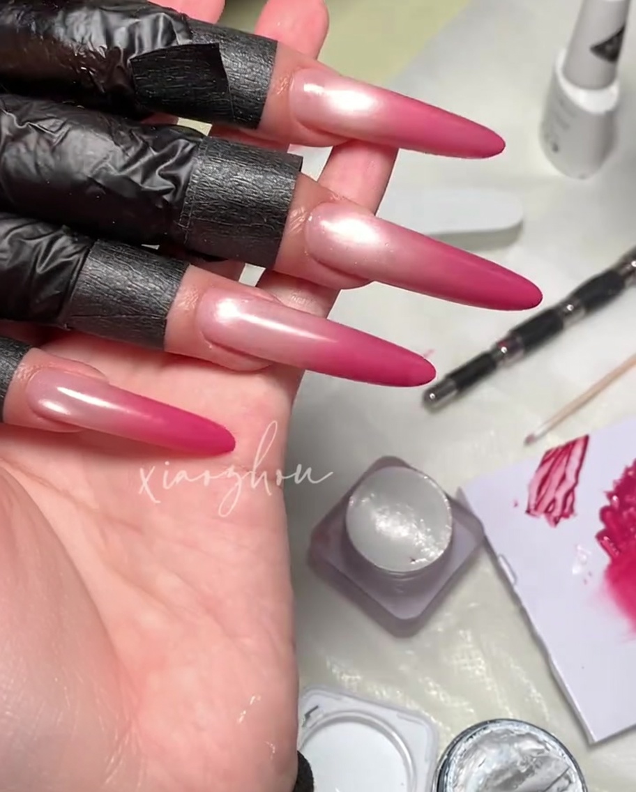 Ein Pinsel trägt einen klaren, glänzenden Top Coat über ein Magenta-Magnetgel-Nageldesign auf.