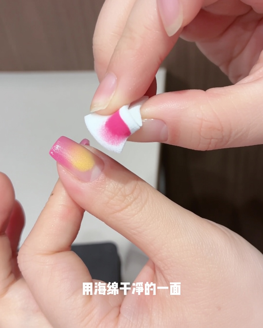 Ein Schwämmchen wird verwendet, um das gelbe Gel vorsichtig über den Nagel zu tupfen und zu verteilen, um eine blütenblattartige Form zu kreieren.