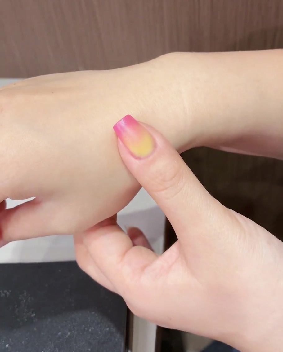 Ein Fingernagel mit dem fertigen Tulpendesign, das unter einer UV/LED-Lampe ausgehärtet wird.