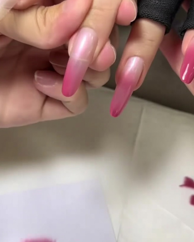 Eine Nahaufnahme der Nagelspitze, auf die die letzte, dunkelste Schicht Rosa aufgetupft wird, um den Farbverlauf abzuschließen.