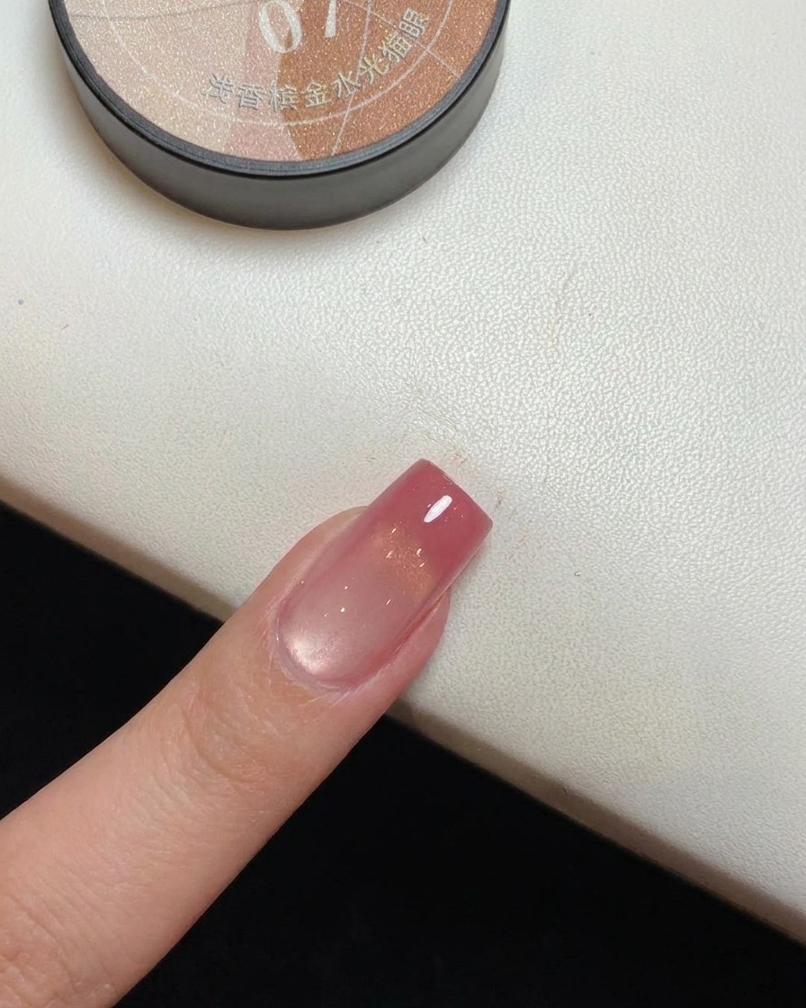 Nahaufnahme eines Nagels mit goldenem Magnetschimmer, der unter einer UV-Lampe aushärtet.