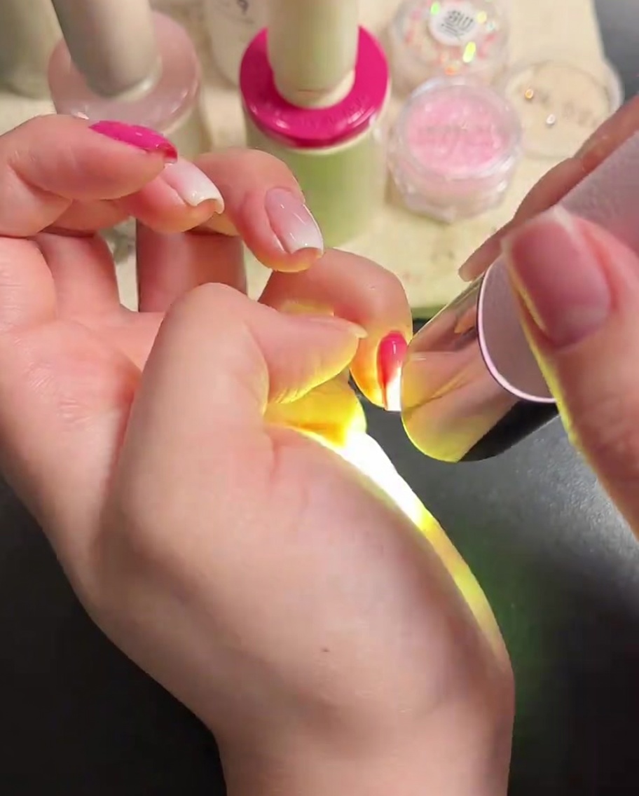 Ein Nagelpinsel trägt einen klaren, glänzenden Top Coat auf die manikürten Nägel auf.