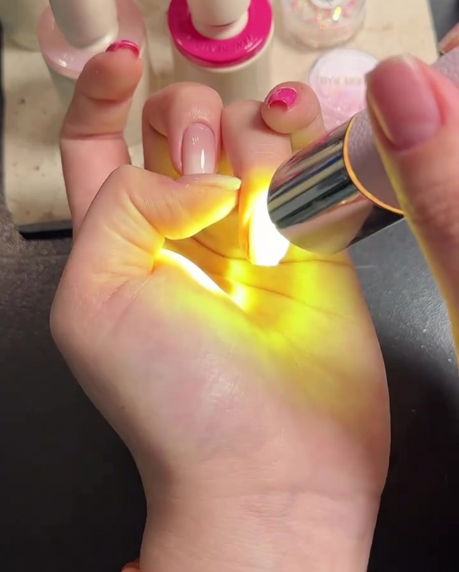 Eine Hand unter der LED-Lampe beim Aushärten des Top Coats.