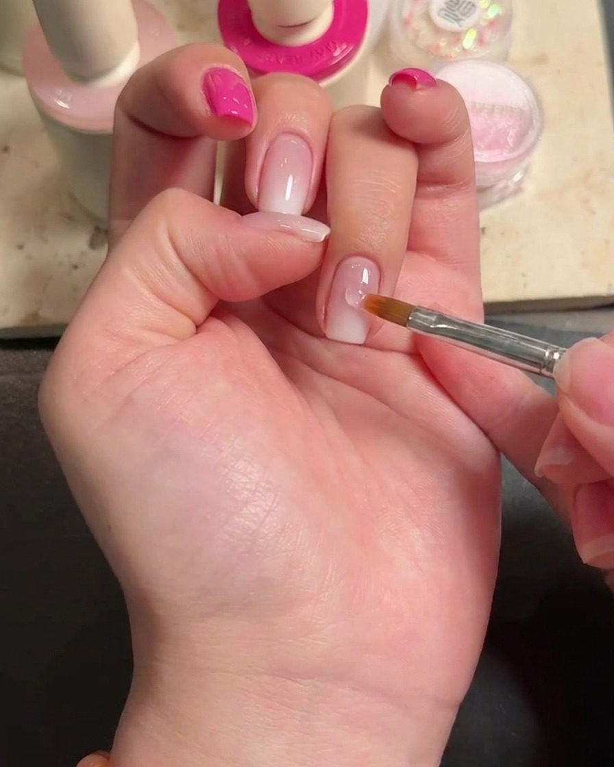 Nahaufnahme eines Tropfens Nagelkleber auf dem Ringfingernagel.