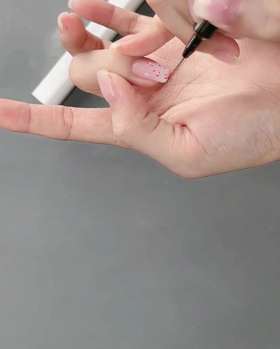 Eine Hand unter einer Nagellampe, um die frisch gezeichneten Linien zu härten.
