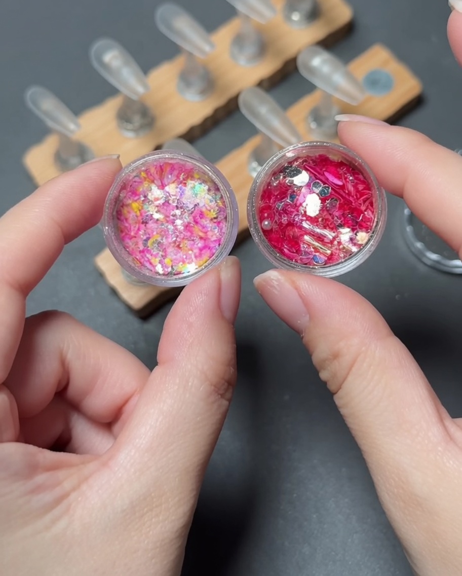 Ein Pinsel, der lebendige, mehrfarbige Pailletten auf den Spitzenbereich eines Press-on-Nagels platziert.