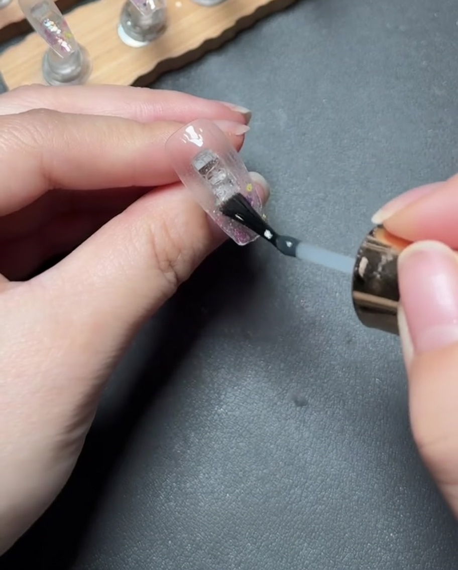 Auftragen eines klaren, dicken Aufbau-Gels über die mit Glitzer bedeckte Nagelspitze.