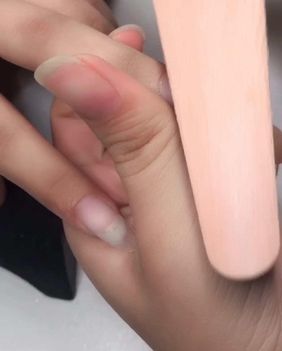Nahaufnahme einer Nagelfeile, die die Oberfläche eines Nagels anbuffert, um ihn für die Gelschicht vorzubereiten.