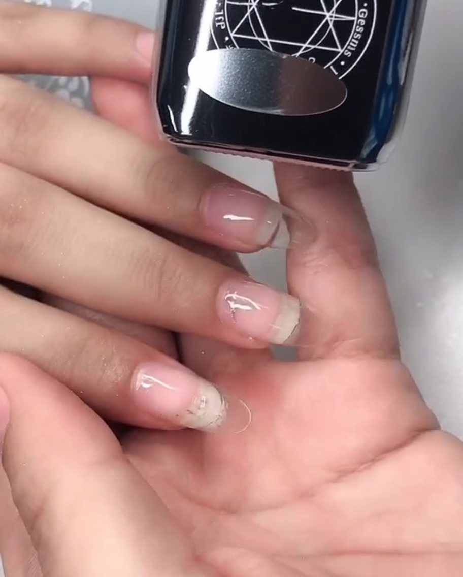 Nahaufnahme eines Mirror-Finish-Top-Coat-Gels, das auf den Nagel aufgetragen wird.